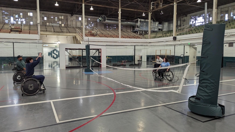 Adaptive sports day participants in wheelchairs playing sit volleyball
