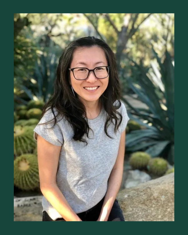 Image of Mia Mingus in a gray t-shirt while sitting in front of trees. 