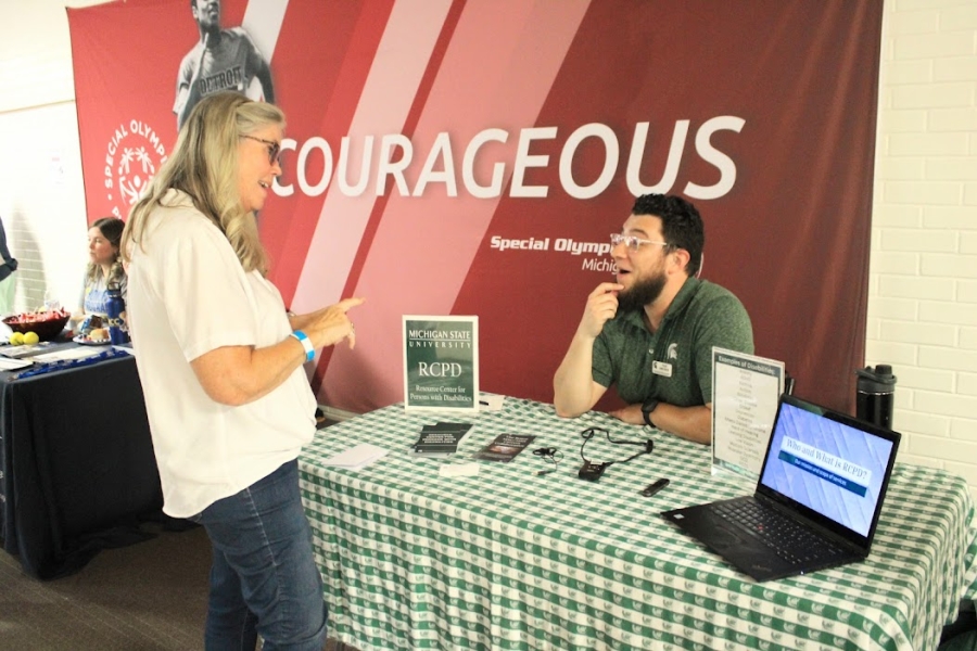 Tyler sitting behind a table and interacting with a woman at the event.