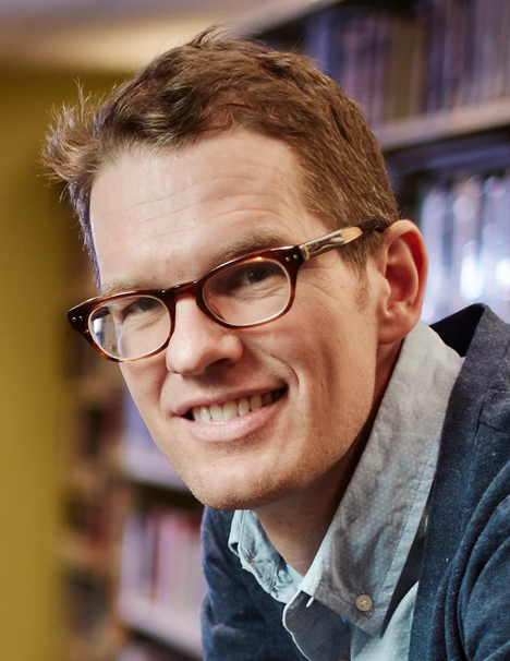 Headshot photo of Jay Dolmage wearing glasses, a collard dress shirt and has short sandy blonde colored hair.