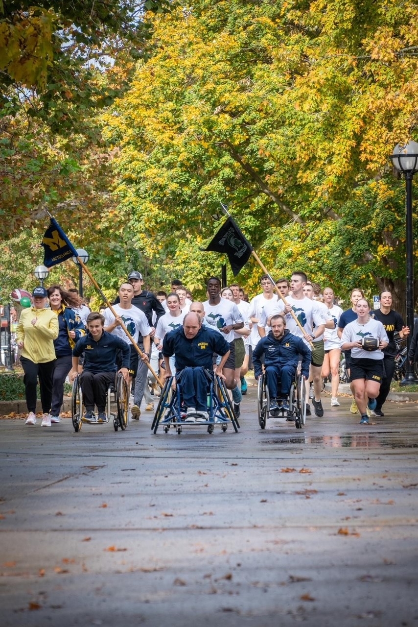 ROTC Cadets along with student athletes in wheelchairs approaching finish line